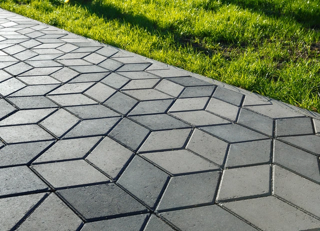 Patterned concrete sidewalk beside a green lawn